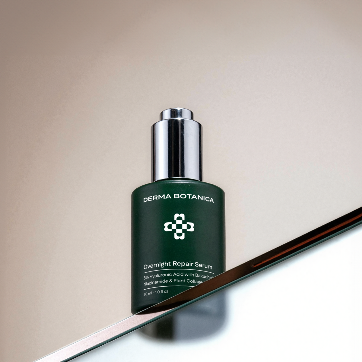 Derma Botanica Overnight Repair Serum bottle on a reflective surface with a neutral background