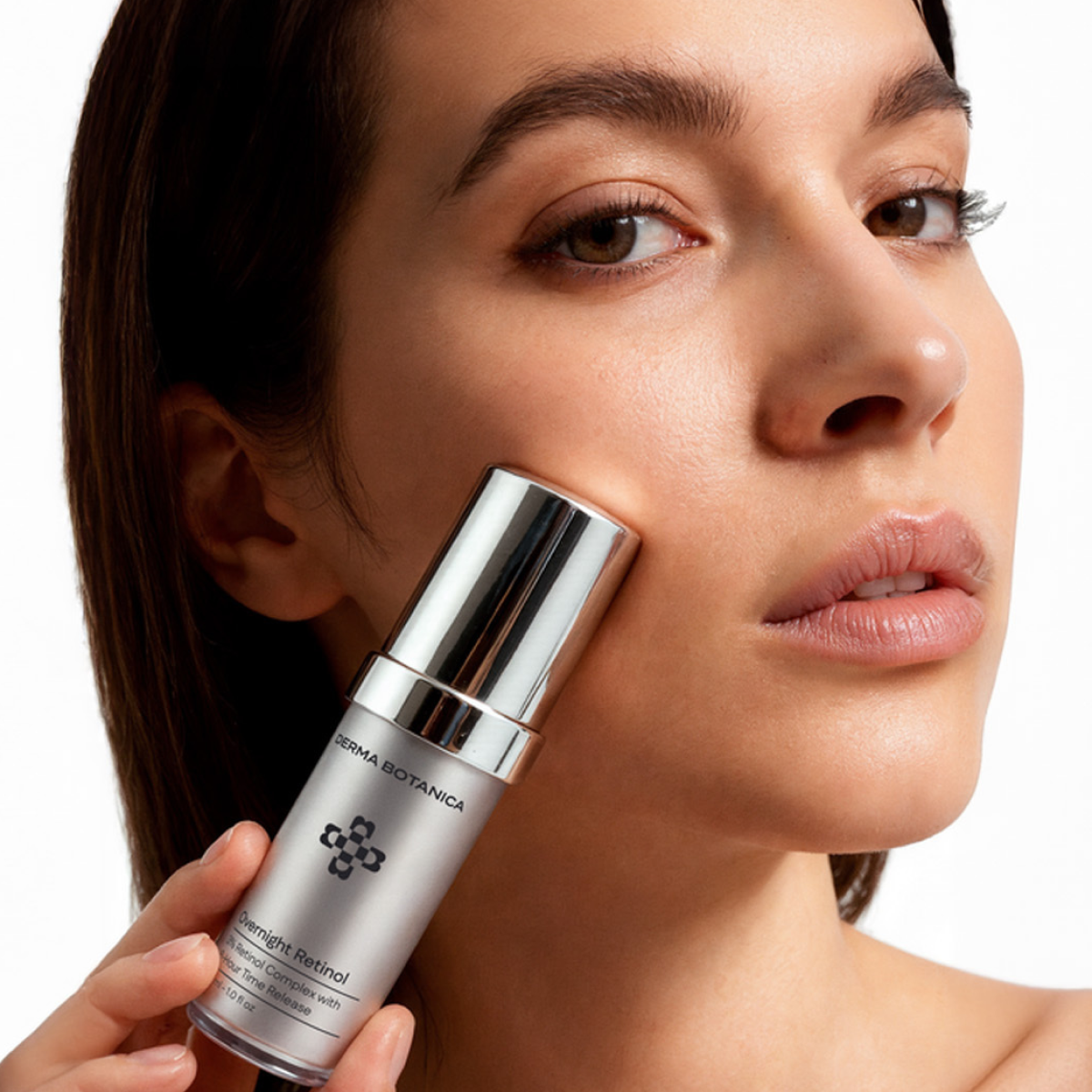 Woman holding a Derma Botanica Overnight Retinol Serum close to her face.